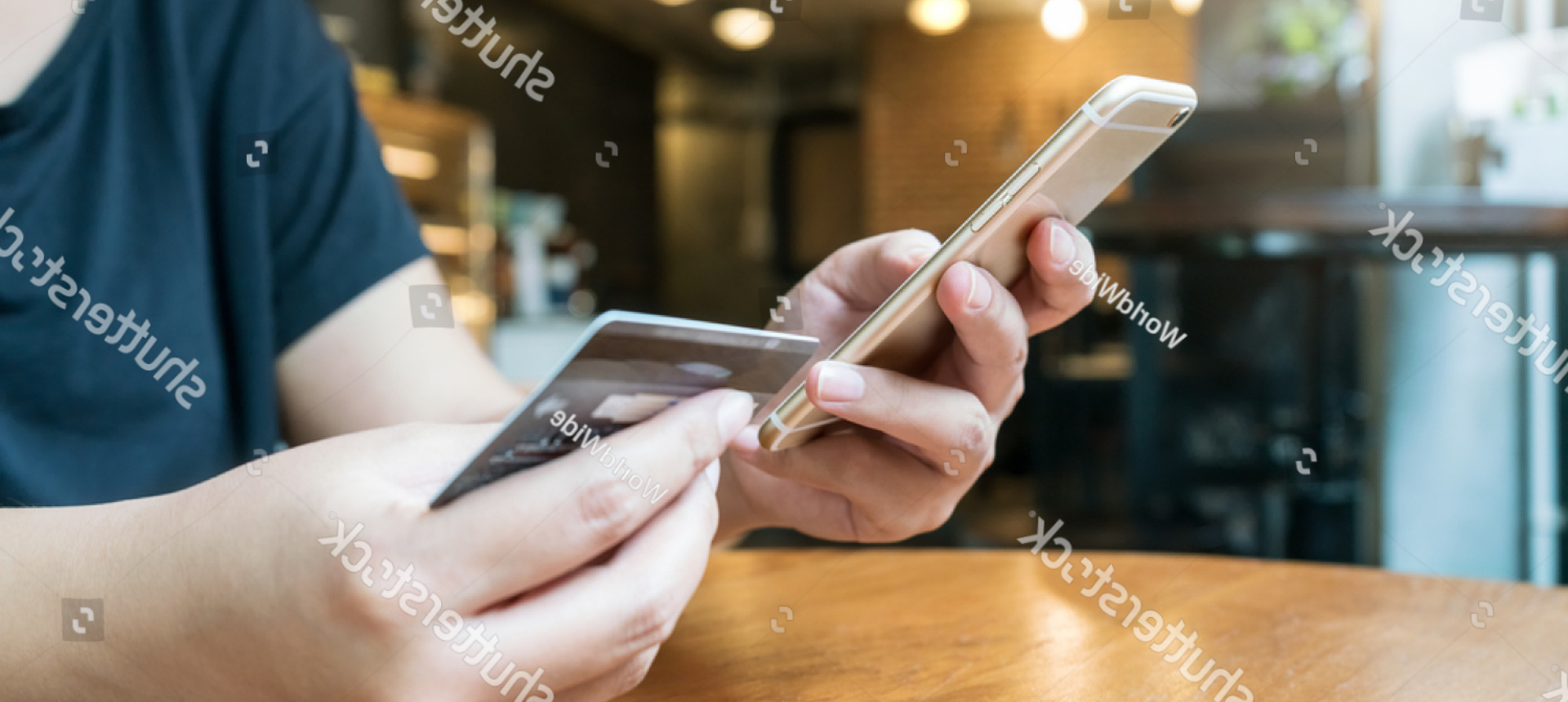 Mãos segurando cartão e celular sobre a mesa - Matera