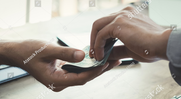 Mão feminina entregando dinheiro a uma mão masculina em uma mesa de negócios - Matera