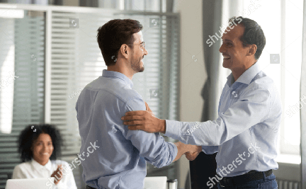 Dois homens de social apertando as mãos e sorrindo.